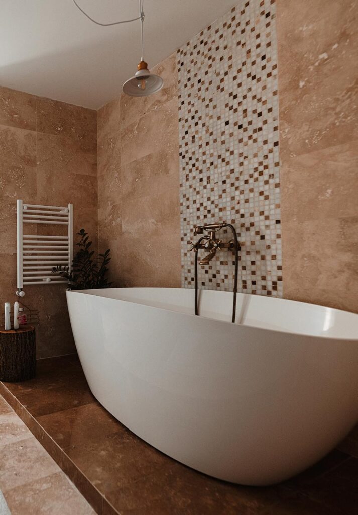 A master bathroom transformation by a home remodeling team in Plymouth, MI, featuring a freestanding soaking tub and natural stone tiles.